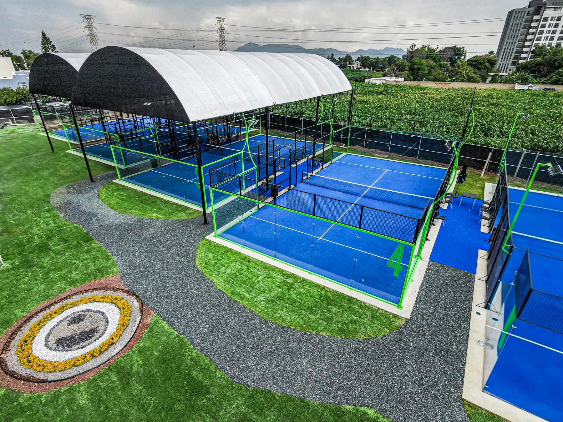 Vista aérea de las canchas de Imperial Padel Academy y el escudo en el jardín